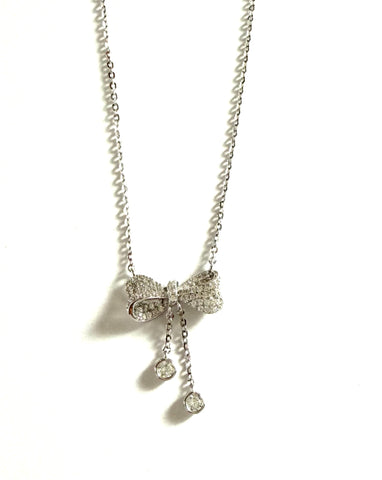 Sterling silver chain necklace with a cubic zirconia bow and hanging bezel stones.